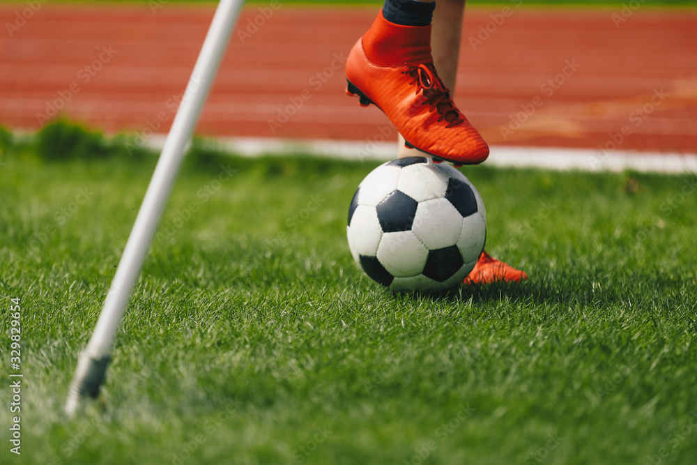 Close-up image of soccer player with ball on grass training field. Athlete in soccer sportswear and soccer boots