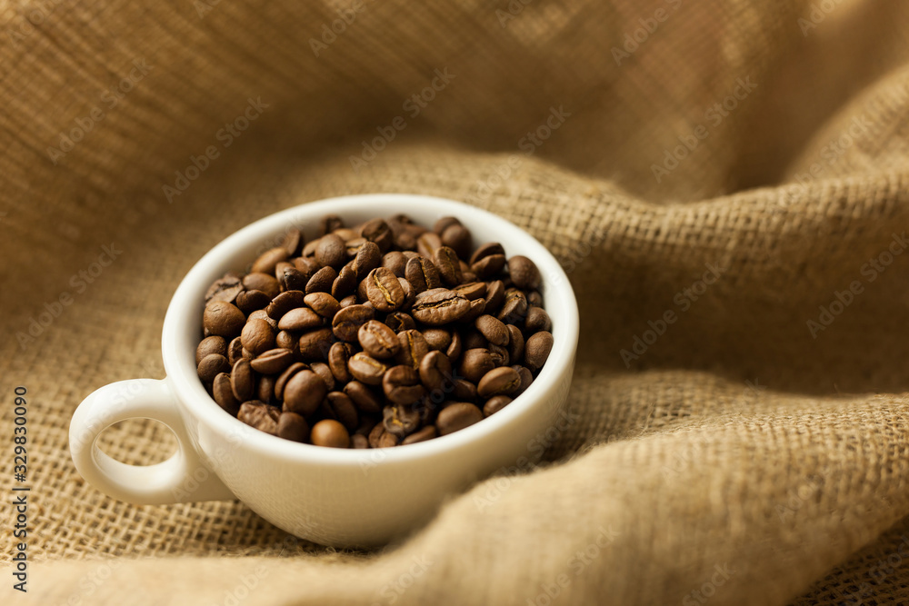 Fototapeta premium A scattering of coffee beans with a cup of coffee.