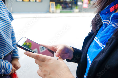 Women hand pointing finger on screen smartphone on street background in day atmospheric city