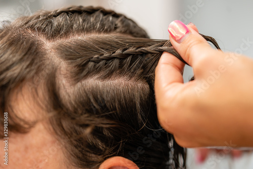 Details of the hairstyle of a young woman with braids, curls and flowers