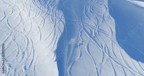 One skier going downhill off-piste in the Swiss Alps. A person skiing. Captured by drone.