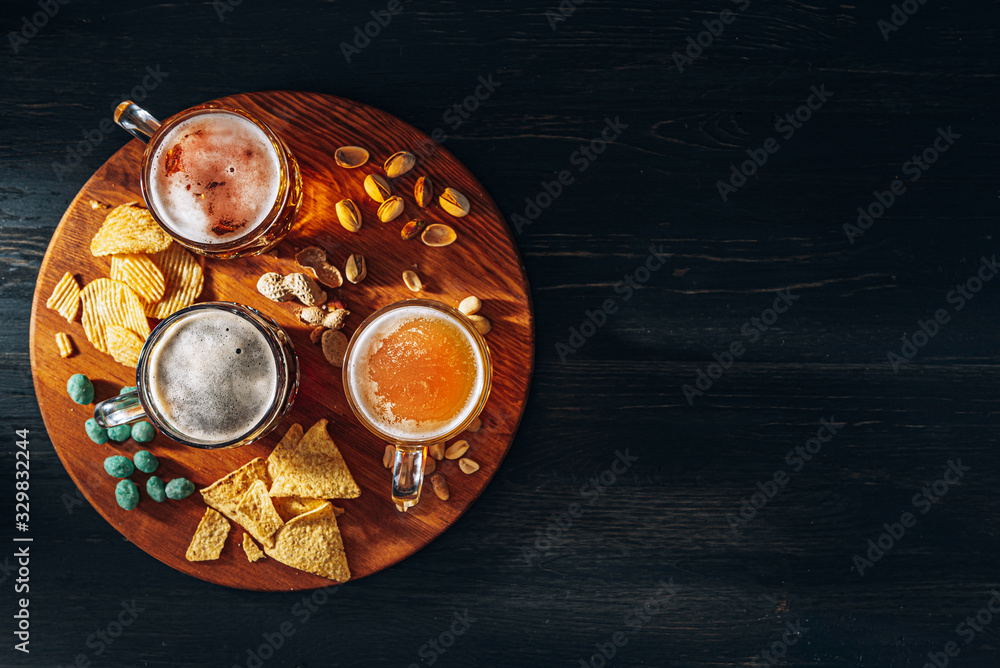 three glasses of expensive craft beer, classic and unfiltered and dark in a glass on the table with a snack of peanut and pistachio chips and nachos three glasses of expensive craft beer, classic and unfiltered and dark in a glass on the table with a snack of peanut and pistachio chips and nachos