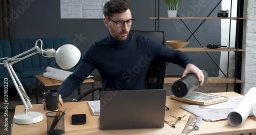Young Architectural Engineer starting to work at Office. Loft style, minimalistic interior. Professional Architect going to work at earlier morning, having cup of Coffee. Hipster Engineer.Architect.