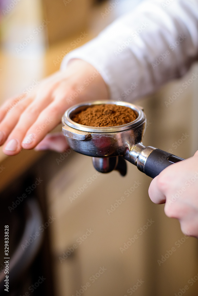 Hand of barista holding coffee machine holder filled with coffee Hand of barista holding coffee machine holder filled with coffee