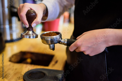 Hand of barista holding coffee machine holder filled with coffee