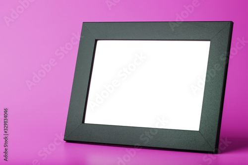 Black photo frame with an empty space on a pink background.