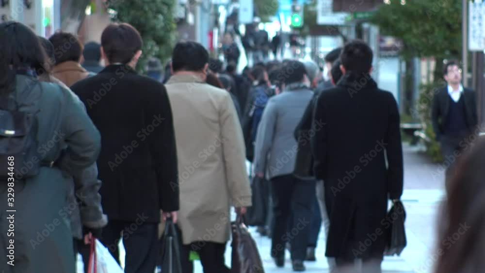 TOKYO, JAPAN - MARCH 2020 : View of crowd of people walking down the street in busy morning rush hour. Many commuters going to work. Japanese business man and woman, job and lifestyle concept. TOKYO, JAPAN - MARCH 2020 : View of crowd of people walking down the street in busy morning rush hour. Many commuters going to work. Japanese business man and woman, job and lifestyle concept.