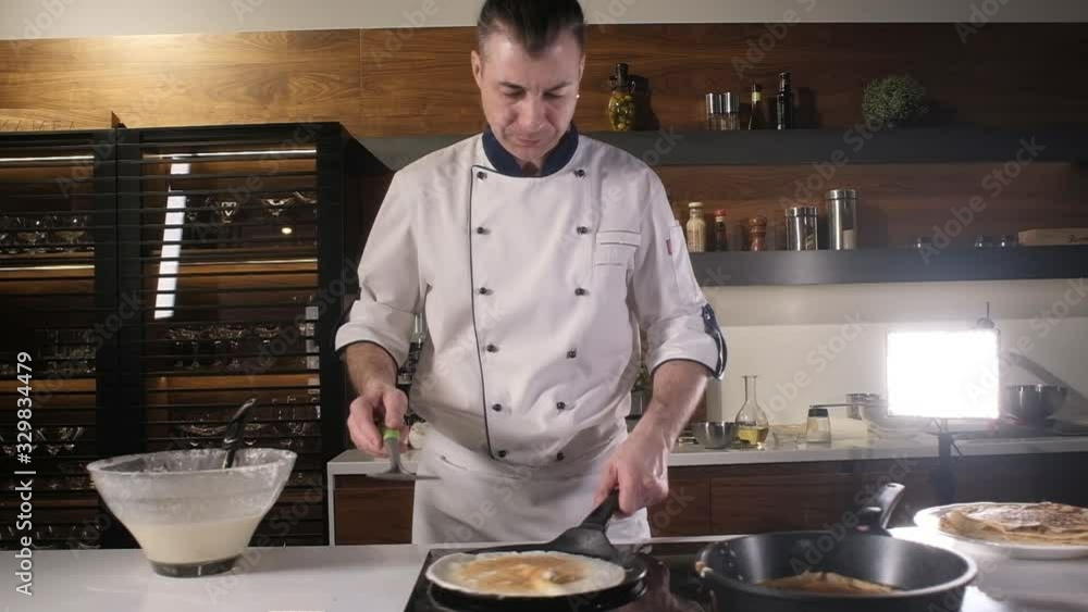cooking pancakes in kitchen. Fast food. adult cook in apron turns pancakes on a hot pan. The process of creating a dessert. chef cooks in the restaurant 's kitchen. Preparing a delicious Breakfast. cooking pancakes in kitchen. Fast food. adult cook in apron turns pancakes on a hot pan. The process of creating a dessert. chef cooks in the restaurant 's kitchen. Preparing a delicious Breakfast.