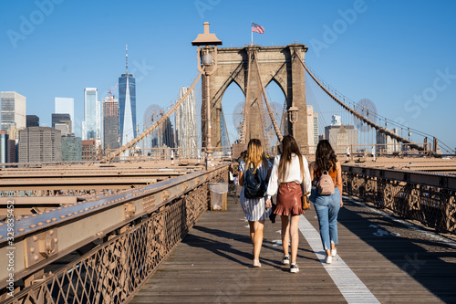 Three girls walking on the Brooklyn Bridge with the New York skyline on the back © Gianandrea Villa