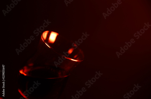 Studio photography of isolated shiny tulip liquor sherry glass illuminated by red light  Focus on glass rim left 