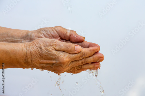 Senior woman washing her hands in white background, Close up & Macro shot, Selective focus, Prevention from covid19, Bacteria, Healthcare concept