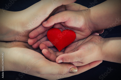 adult and child hands holding red heart, health care, donate and family insurance concept,world heart day, world health day, CSR concept, adoption foster family.Image is tinted