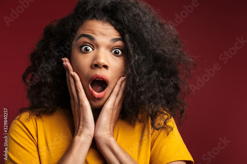 Image of shocked african american woman screaming and grabbing her face