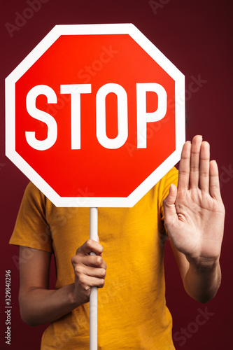 Image of outraged young brunette african american woman holding stop sign