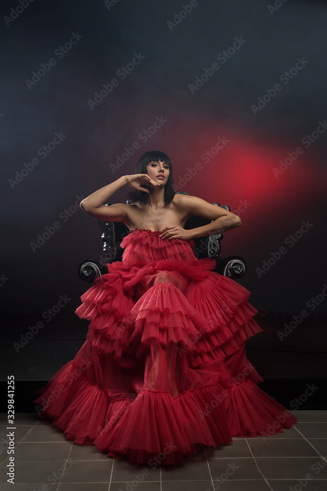 Female model in red dress on chair Female model in red dress on chair