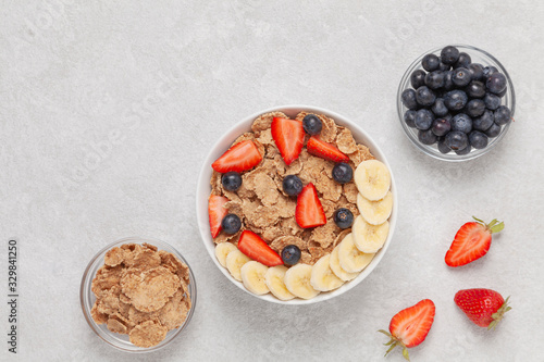 Fotografie Multigrain wholewheat healthy cereals with banana and fresh berries blueberry, strawberry for breakfast