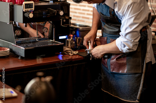 The barista with blue shirt making coffee with a espresso machine.