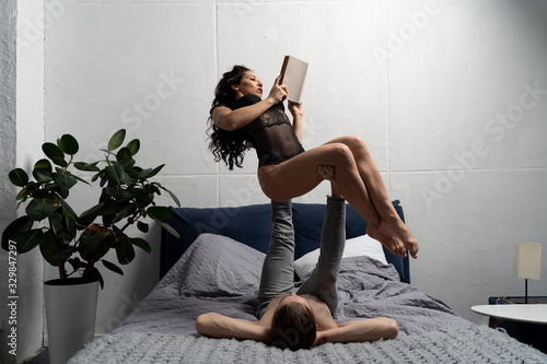 Couple spending time together reading book and making acrobatic balance at home. concept of self-development and creativity. photo