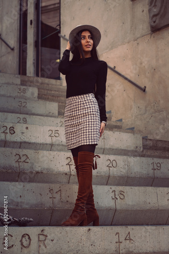 stylish girl in a hat with long hair posing on the steps of the building