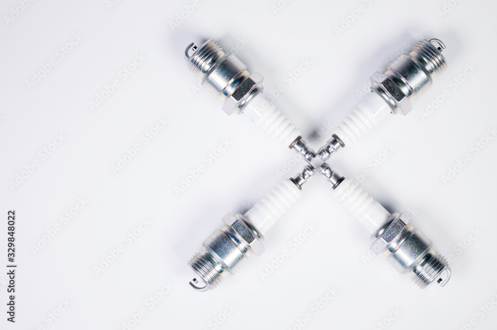Subject shooting on a gray background. new four spark plugs, spare parts for a gasoline engine. The concept of new auto parts and maintenance Subject shooting on a gray background. new four spark plugs, spare parts for a gasoline engine. The concept of new auto parts and maintenance