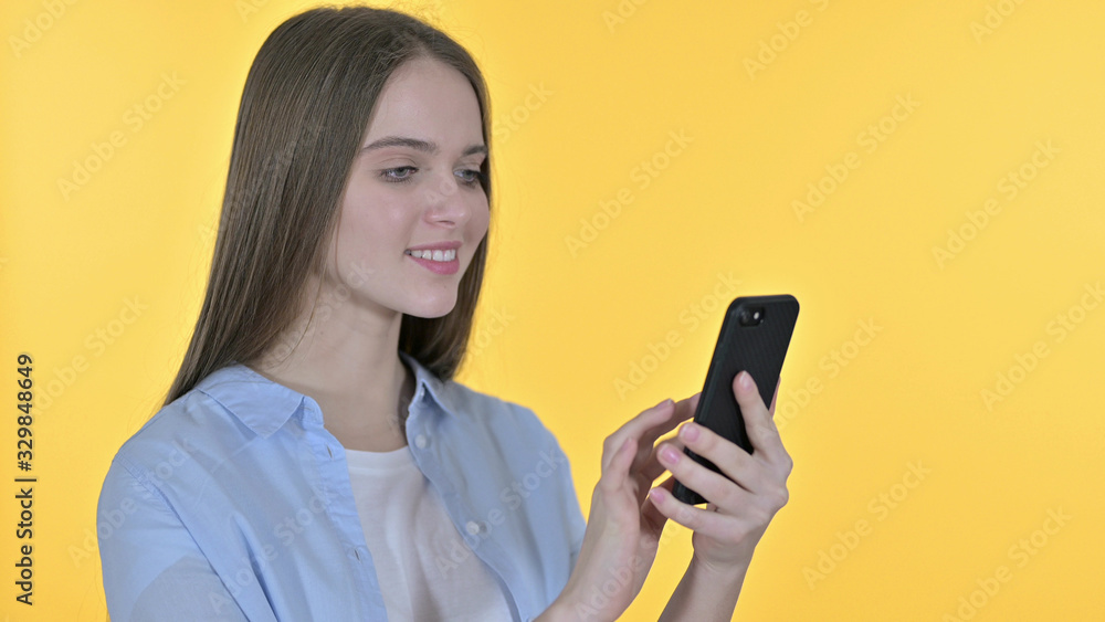 Cheerful Beautiful Woman using Smartphone, Yellow Background Cheerful Beautiful Woman using Smartphone, Yellow Background