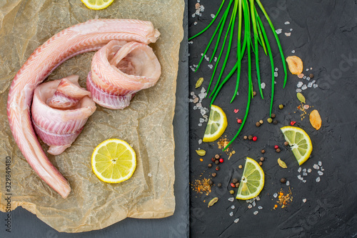 fresh fish fillets , dogfish  row fillets ,lemon herbs , pepper, salt on black background