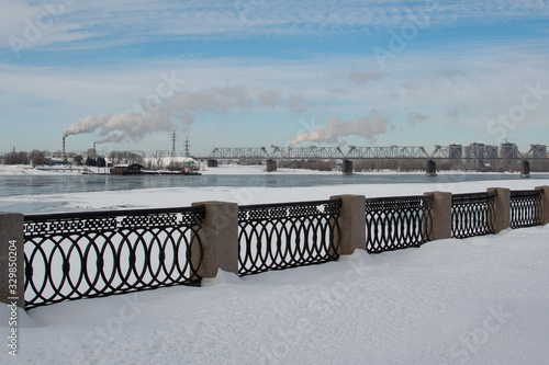 Urban landscape in spring, melting snow on the river in spring, Smoking chimneys of a thermal power plant © seregg