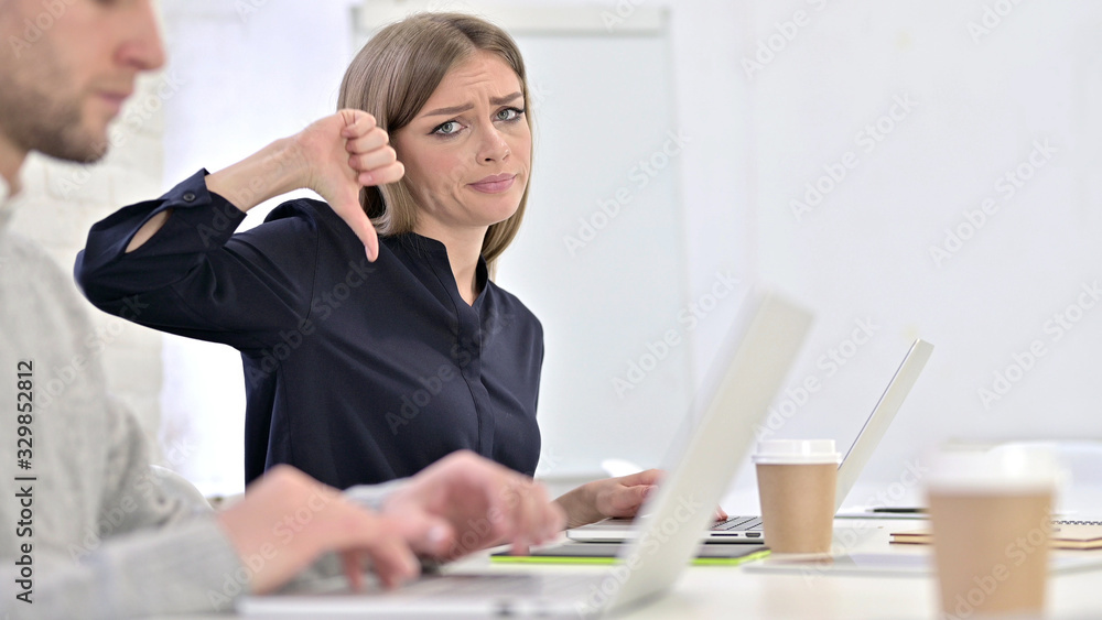 Disappointed Creative Woman showing Thumbs Down in Office Disappointed Creative Woman showing Thumbs Down in Office