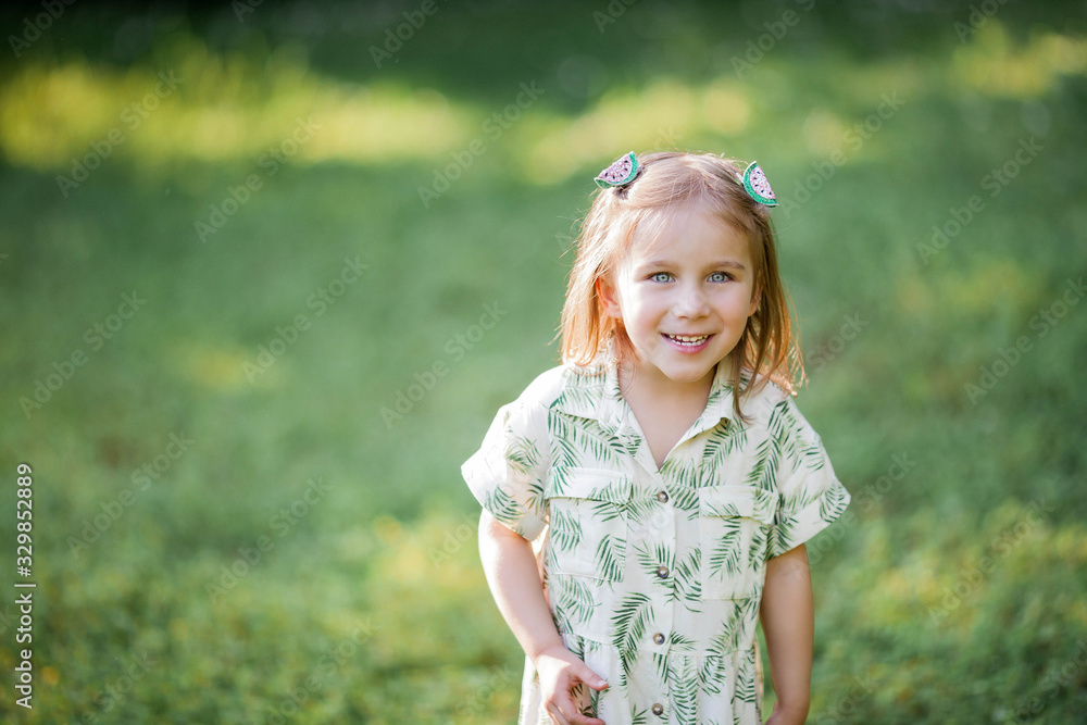 Little cute girl is sitting on the grass. Happy girl in the park. Summer. Little cute girl is sitting on the grass. Happy girl in the park. Summer.