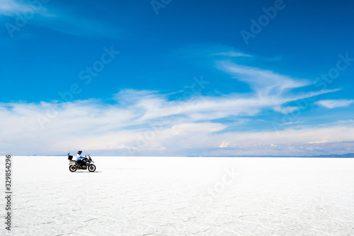 Tourist with equipment riding on motorbike in sunshine Salar de Uyuni