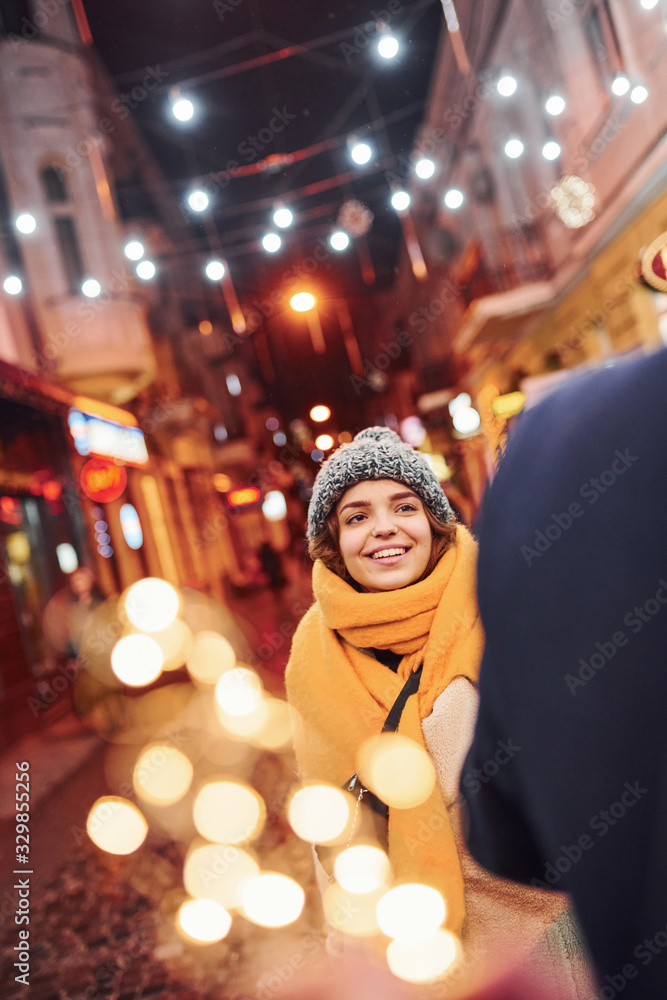 Happy young couple in warm clothes is on christmas decorated street together Happy young couple in warm clothes is on christmas decorated street together