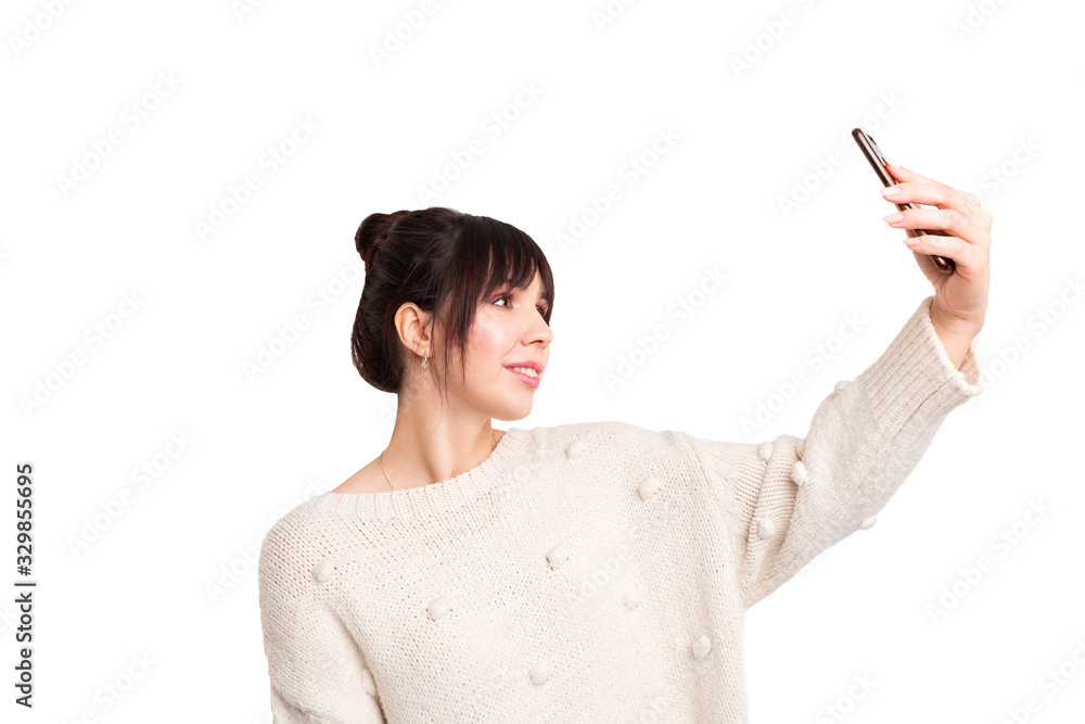 Smiling caucasian brunette holding a phone in left hand and making a selfie. Isolated on white background. Smiling caucasian brunette holding a phone in left hand and making a selfie. Isolated on white background.