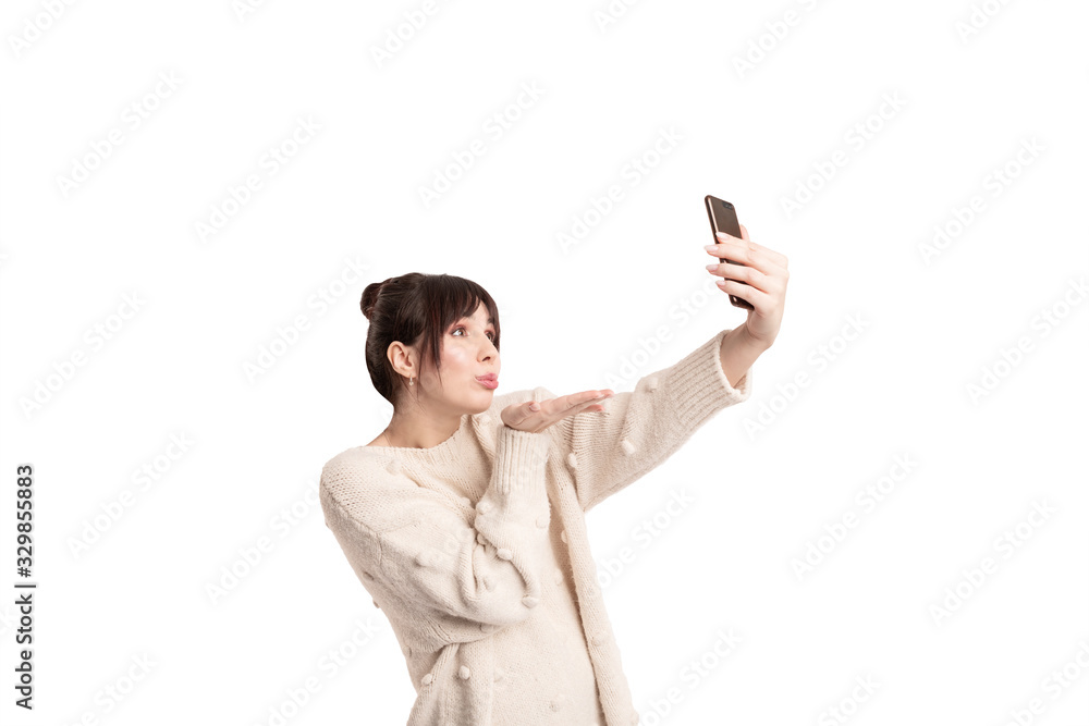 Woman sending air-kiss to someone and making a video on smartphone. Isolated on white background studio photo. Woman sending air-kiss to someone and making a video on smartphone. Isolated on white background studio photo.