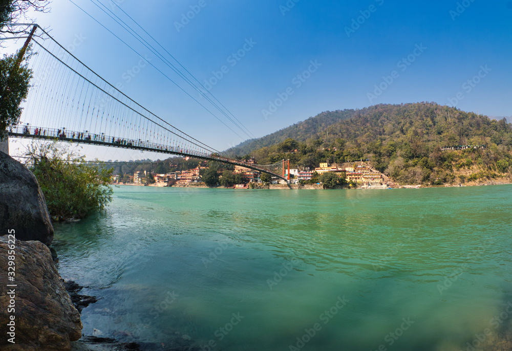 View of Ganga river embankment, Lakshman Jhula bridge and Trimbakeshwar Temple in Rishikesh, Uttarakhand, India View of Ganga river embankment, Lakshman Jhula bridge and Trimbakeshwar Temple in Rishikesh, Uttarakhand, India
