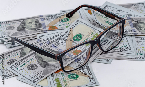 Glasses lies on background of scattered American dollars