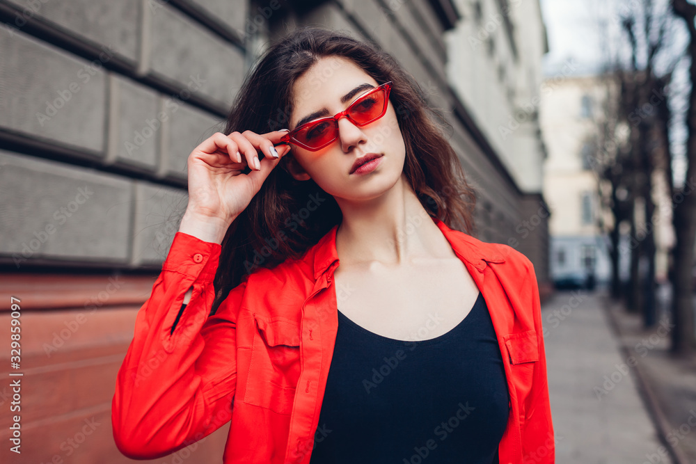 Street female fashion. Portrait of stylish young hipster woman wearing red shirt glasses outdoors. Spring accessories Street female fashion. Portrait of stylish young hipster woman wearing red shirt glasses outdoors. Spring accessories