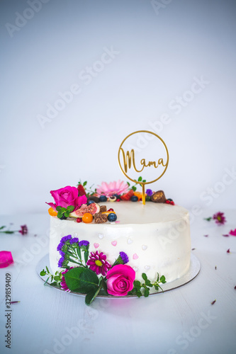 Sweet white cheesecake torte with fresh fruits and rose flowers for mother mama on white wooden table