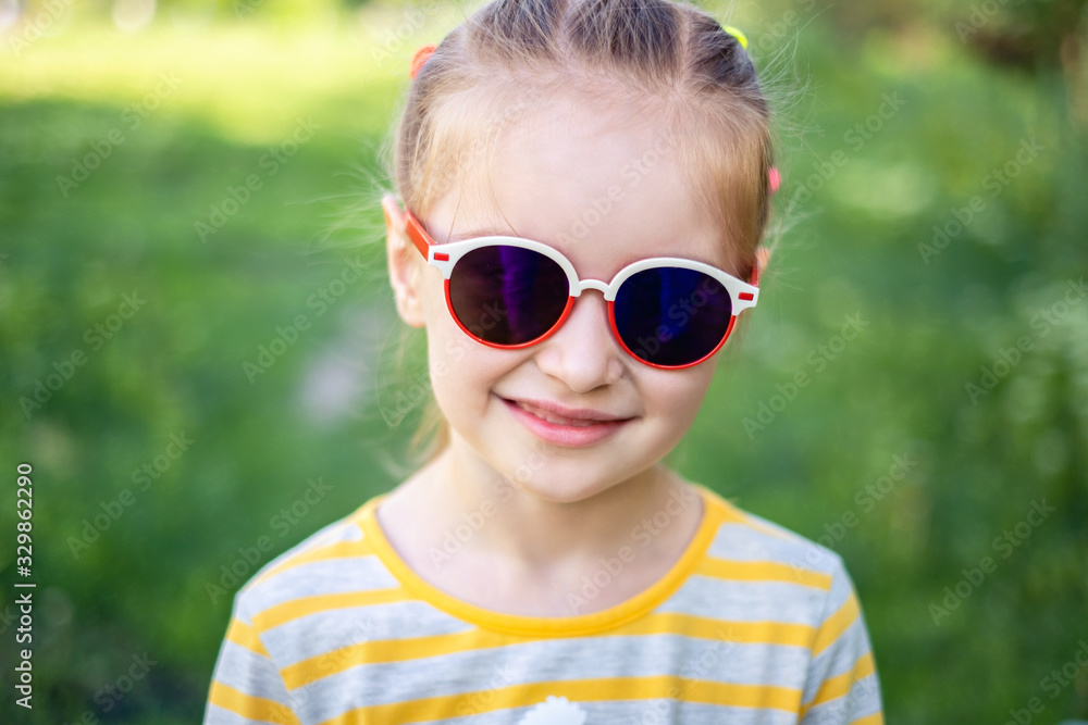 Portait of fashion girl child in modern pretty sunglasses on background of green park Portait of fashion girl child in modern pretty sunglasses on background of green park