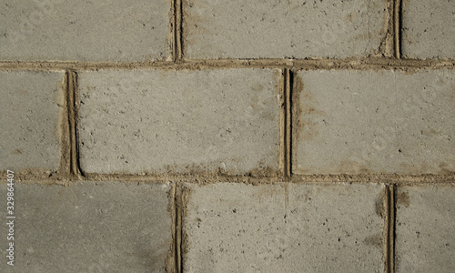 Wall of large, blocky gray bricks with sloppy cement joints. Texture closeup.
