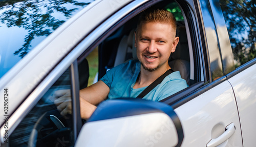 Young attractive man in white car, lookind at the camera