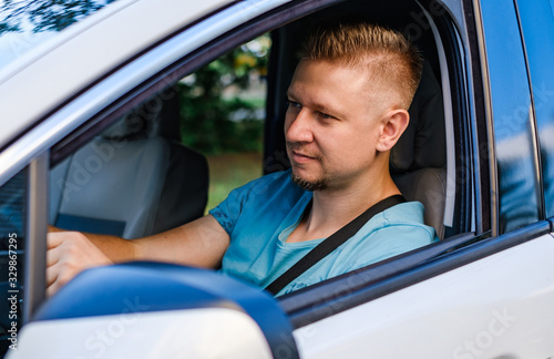 Young attractive man as driver in white car, outdoors