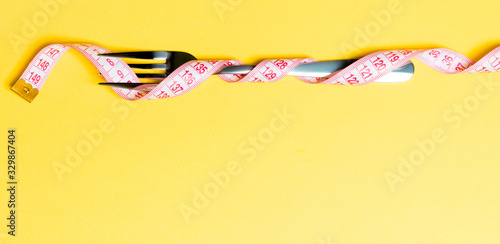 Εκτύπωση καμβά Composition of curled wrapped measuring tape and fork on yellow background