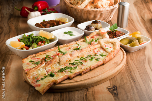 turkish cheese pide with garnitures on wooden table photo