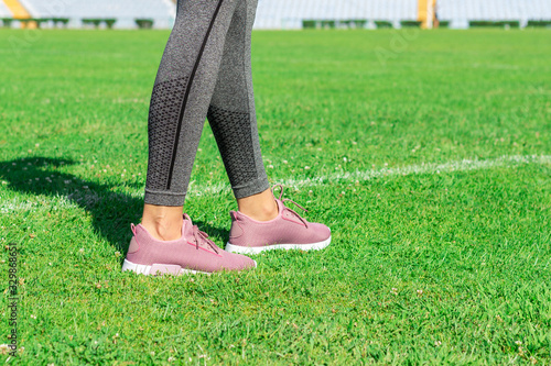 Crop image of female sporty legs and feet in running shoes at the stadium