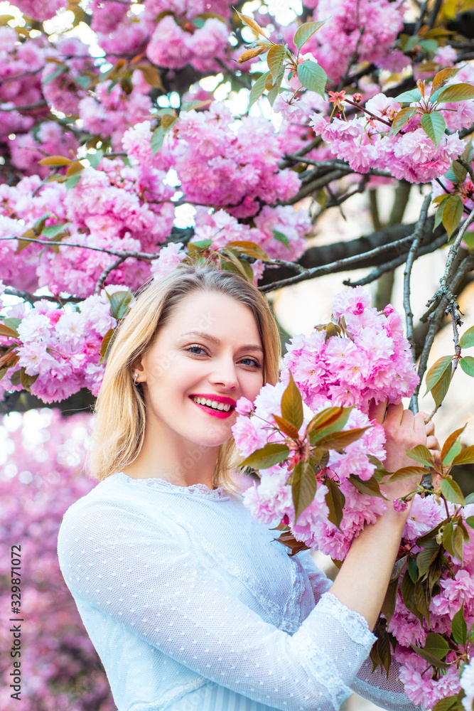 Fototapeta premium Womens day, 8 march. Beautiful woman with blooming Sakura tree and sunny day.