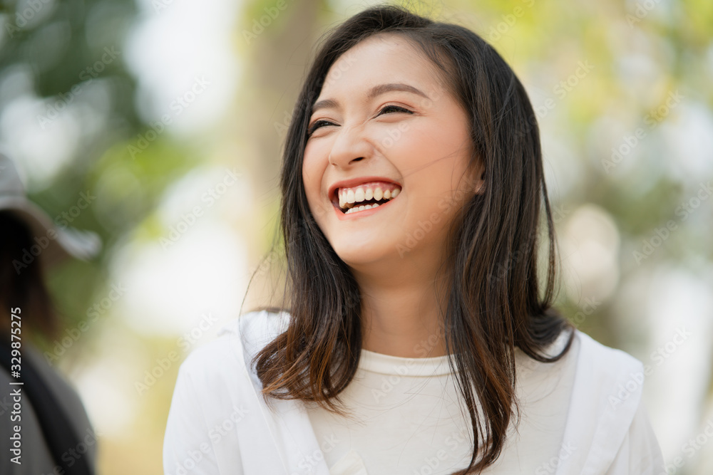Portrait shot of happy, successful, attractive bearded of Asian woman with big smiling with a confident look toward the camera at a blur park background with copy space in natural sunlight. Portrait shot of happy, successful, attractive bearded of Asian woman with big smiling with a confident look toward the camera at a blur park background with copy space in natural sunlight.