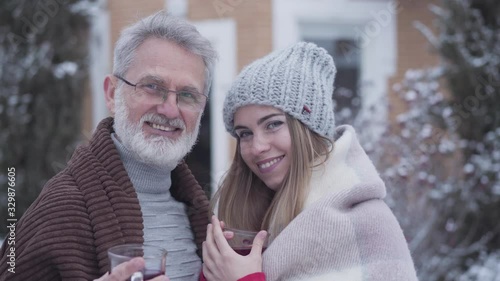 Portrait of Caucasian couple with age difference looking at each other with love and smiling at camera. Happy senior man and young woman posing outdoors on winter day. Love, age gap, lifestyle. photo