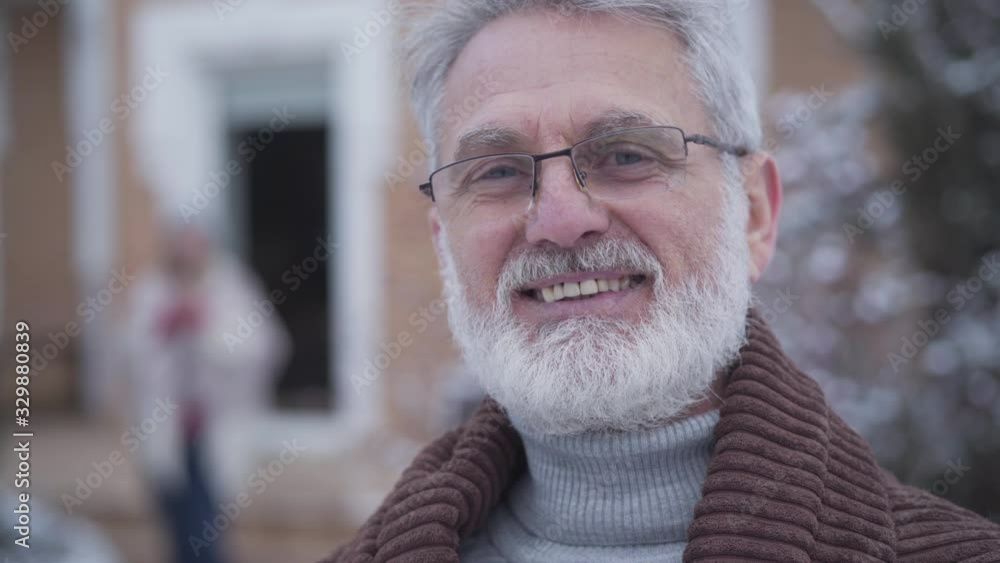 Close-up face of handsome graceful man in eyeglasses smiling at camera. Senior grey-haired Caucasian retiree posing outdoors on winter day. Lifestyle, leisure, relaxation. Close-up face of handsome graceful man in eyeglasses smiling at camera. Senior grey-haired Caucasian retiree posing outdoors on winter day. Lifestyle, leisure, relaxation.