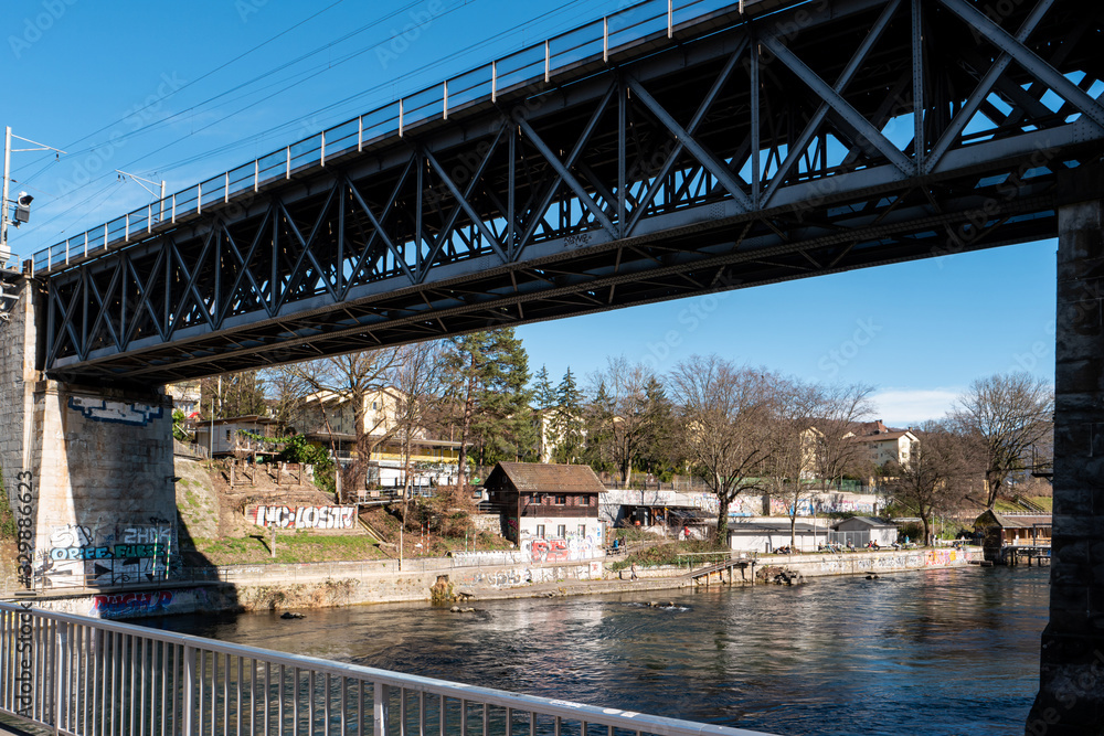 Obraz premium Zurich city view of the Limmat river and industrial buildings and steel bridge in the background sunny day Switzerland.