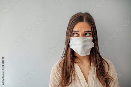 Woman wear with protective face mask. Young woman with face mask. Face of a mask-wearing woman with fear in the eye. Beautiful young woman wearing contamination mask at home